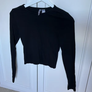 Svart ribbad långärmad topp H&M - Långärmad och croppad topp med ribbat material, perfekt bastopp!
