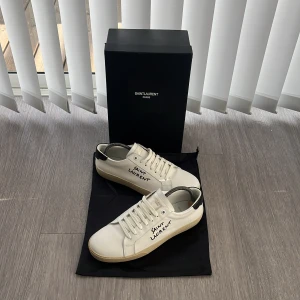 Vita skor från Saint Laurent - Säljer dessa feta Saint Laurent skor som är i super skick. De är vita med svart häl och snygg handskriven logga. De är perfekt för hela året runt och både vardagsstil och på fest