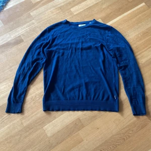 Mörkblå stickad tröja Jack & Jones - Snygg mörkblå stickad tröja från Jack & Jones i storlek S. Tröjan har rund hals, långa ärmar och ribbade muddar vid ärmslut och nederkant. Perfekt för dig som gillar enkel och stilren design med en chill vibe.