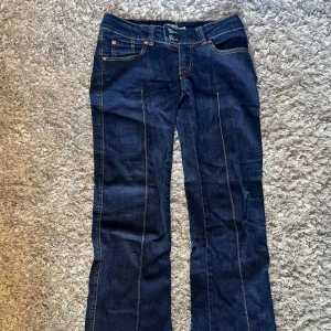 Mörkblå bootcut - Mörkblå bootcut jeans med snygg söm längs benen och snygga knappar! 