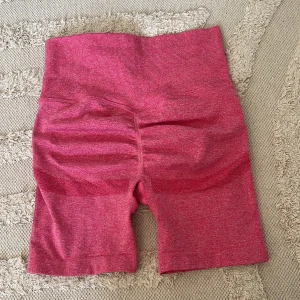 Rosa träningsshorts med scrunch - Snygga rosa seamless shorts med hög midja och ribbade detaljer. Materialet är stretchigt och består av polyamid, polyester och elastan, vilket gör dem perfekta för träning. De har scrunch-effekt bak för extra shaping och sitter tight mot kroppen.