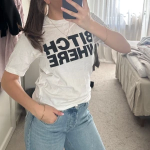 Vit Dsquared2 t-shirt med tryck - Cool vit t-shirt från Dsquared2 med svart statement-tryck 'BITCH WHERE' på framsidan och Dsquared2-logga på ryggen. Klassisk rund hals och korta ärmar. Perfekt till jeans för en chill och edgy look. Gjord i mjuk bomull.