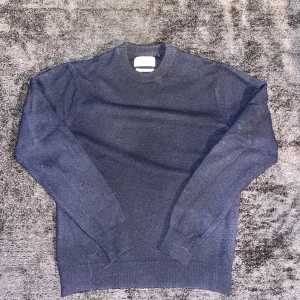 Mörkblå merinoull tröja med rund hals - Tröjan är XS men passar mer som en S.                             Säljer en stilren mörkblå stickad tröja med rund hals och ribbade muddar vid ärmslut och nederkant. Tröjan har en klassisk passform och är perfekt för dig som gillar enkel och clean stil. Passar till jeans eller chinos för en chill look.