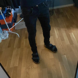 Svarta Luke jeans från Lee W30 L32 - Säljer ett par svarta Luke jeans från Lee i storlek W30 L32. De har en slim passform med raka ben och klassisk femficksdesign. Jeansen är tillverkade i bomull och har snygga svarta sömmar och Lee-logga på bakfickan.