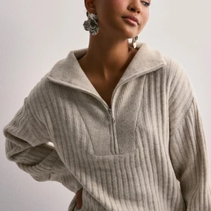 Beige ribbad half zip tröja Pieces - Supermysig beige ribbad tröja från Pieces med half zip och bred krage. Tröjan har långa ärmar med loose passform och är stickad i mjukt material. Perfekt för chill dagar och snygg att styla med jeans eller mjukisbyxor. Använd max 2 gånger då jag känner mig obekväm i stickat. Finns inte kvar längre i pieces sortiment. Ordinarie pris 500 