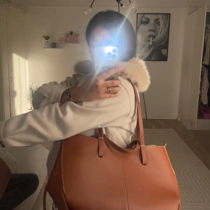 Brun handväska från Polène i skinn - Snygg handväska från Polène i brunt skinn med vita kontrastsömmar och guldfärgad logga. Fint för skola. Påsen finns med😊har använd ett år.