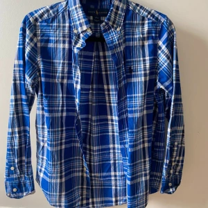 Blårutig skjorta från Ralph Lauren XS - Tvärfet blårutig skjorta från Ralph Lauren med klassisk button-down krage och broderad logga på bröstet. Skjortan är stl L i barnstorlek vilket motsvarar XS i vuxenstorlek. 