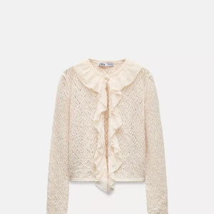 Beige stickad kofta med volang Zara - Supersöt beige stickad kofta från Zara med lång ärm och genomgående hålmönster. Koftan har volangdetaljer i chiffong längs krage och knappslå, samt en liten knapp framtill. Använd kanske 1 gång. Skriv för prisförslag, frågor eller bilder🩷