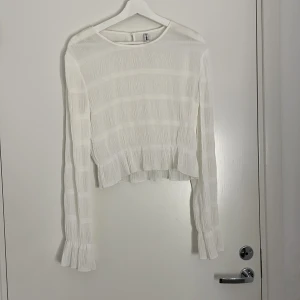 Vit volang topp - Vit volang topp med knapp i nacken. Storlek L men passar ävenM/S om man vill ha den lös, den är inte så oversized. 