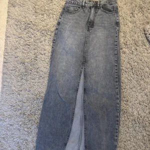 Grå lång jeanskjol från Stradivarius - Säljer en snygg grå lång jeanskjol från Stradivarius med klassisk femficksdesign och hög midja.  Storlek xs 