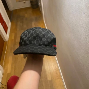 Gg keps - En snygg keps med klassiskt GG-monogram över hela kepsen och gröna/röda detaljer på sidorna. Justerbar rem baktill för perfekt passform. Tillverkad i bomull och polyester, perfekt för dig som vill sticka ut med en lyxig streetstyle.