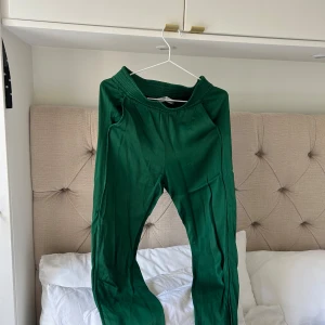 Gröna mjukisbyxor med resårmidja - Snygga gröna mjukisbyxor med bred resår i midjan och avslappnad passform. Byxorna har en slät yta (siden) och är perfekta för chill dagar eller när du vill vara bekväm men ändå se fräsch ut. Lätta att matcha med crop top eller hoodie.