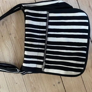 Marimekko väska olkalaukku urbaani - En äldre modell av olkalaukku urbani men i toppen skick. Den är lite större än andra modeller och får plats med 13” dator. 32x30x13 cm. 