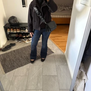 Svart axelväska ifrån NA-KD - Jättefin svart väska med med mycket förvaringsfack inuti. Den är ifrån NA-KD och kan justeras i längden. Säljer då jag ej får användning av den längre.