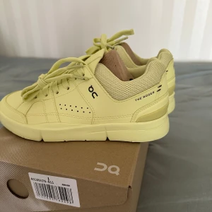 On The Roger Clubhouse sneakers - Snygga On The Roger Clubhouse sneakers i en ljusgul färg. Skorna har en chunky sula, perforerade detaljer på sidorna och ovandel i syntet och mesh. Klassisk snörning och låg modell 