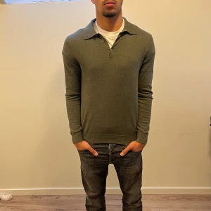 Mörkgrön polotröja från bläck  - Snygg mörkgrön polotröja med diskret polo knappar och klassisk krage. Tröjan har långärmade och en normal passform som sitter skönt. Perfekt att matcha med jeans eller chinos för en clean look. Materialet känns mjukt och är troligtvis bomull eller polyester. Nypris: 799Kr. Mitt pris: 249Kr✅