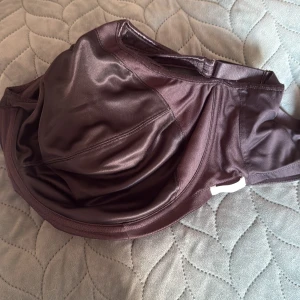 Svart sport bh från Freya - Snygg svart sport bh  från Freya med slät, glansig yta och justerbara axelband. Modellen har hakknäppning bak och är tillverkad i polyester, polyamid och elastan för en bekväm passform. 