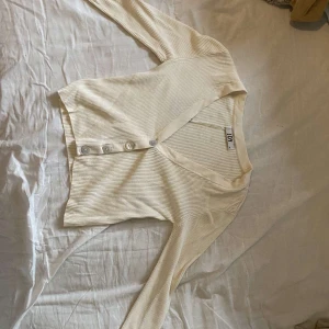 Beige ribbad kofta från JDY - Säljer en beige ribbad kofta från JDY i storlek XS. Koftan har v-ringning, långa ärmar och knäppning med fyra knappar framtill. Perfekt att slänga över en topp för en chill look. Superenkel att matcha med jeans eller kjol.