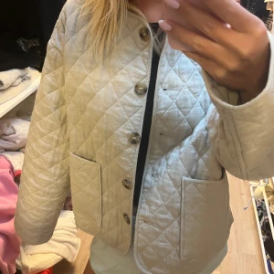 Beige jacka från Zara -  beige jacka från Zara med stora knappar framtill och två rejäla fickor. Jackan har en boxig, loose passform och är perfekt för lager-på-lager. Snyggt rutmönster och rundad halsringning ger en clean vibe.