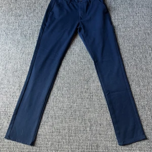 Midnattsblå kostymbyxor från Grunt - Snygga midnattsblå kostymbyxor från Grunt med raka ben och klassisk passform. Byxorna har hällor för bälte, knäppning fram och bakfickor med knapp. Perfekta för en clean och stilren look. Andvända typ 1 gång. Hör av er vid frågor och funderingar😄🙌