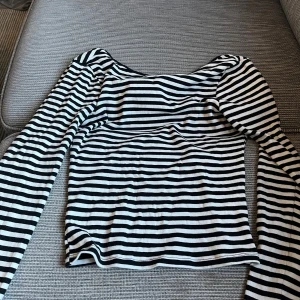 Randig långärmad topp i ribbad bomull - Säljer en svartvit randig långärmad topp med ribbad struktur. Öppen rygg. Från Gina
