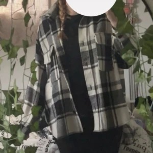 Rutig overshirt från Gina Tricot - Säljer en oversized rutig overshirt från Gina Tricot i svart, grått och beige. Jackan har stora bröstfickor, knappar framtill och klassisk krage. Perfekt att slänga över en hoodie eller t-shirt.