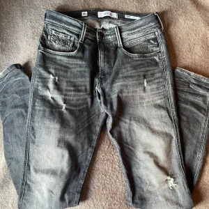 Replay Anbass aged 5 years  - Replay Anbass aged 5 years jeans i grå tvätt med slitna detaljer. Storlek 31x34. Jättebra skick förutom en liten slitning vid början av dragkedjan mellan benen(se sista bilden).