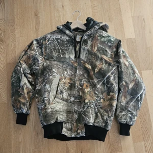 Carhartt camo bomberjacka med huva - Storlek: S - Passar även M. Kemtvättad och Oanvänd i nyskick. Carhartt Jacka x Real Tree