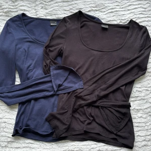 2 långärmade toppar Gina Tricot S - Två basic långärmade toppar från Gina Tricot i storlek S. En är svart och en är mörkblå, båda med rund halsringning och i mjuk bomullsmix. Perfekta att styla med jeans eller kjol. 