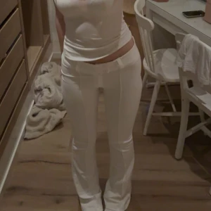 Vita bootcut-kostymbyxor - Snygga vita bootcut-byxor från Gina Tricot med hög midja och två knappar framtill. Byxorna har pressveck längs benen💞