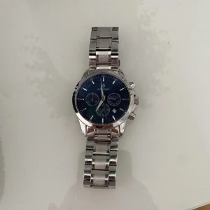 Silverfärgad AKIGHT klocka med blå urtavla - Stilren klocka från AKIGHT med silverfärgad länk i metall och blå urtavla. Klockan har tre mindre urtavlor, datumvisning och tydliga indexmarkeringar. Perfekt accessoar för dig som gillar klassisk design med modern touch.