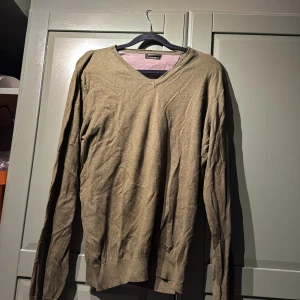 Olivgrön v-ringad tröja Massimo Dutti - Olivgrön v-ringad tröja från Massimo Dutti i mjuk ullblandning. Klassisk och stilren modell med långa ärmar och ribbade muddar. Perfekt för lager-på-lager och snygg till både jeans och chinos.