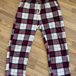 Rutig mjukisbyxa från Lindex, M - Mysiga mjukisbyxor från i återvunnen bomullsblandning. Byxorna har elastisk midja med snörning och avslappnad passform. Perfekta för chill dagar hemma eller när du vill vara extra bekväm.