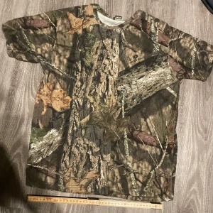 Camouflage t-shirt från Dunelm - Säljer en kortärmad t-shirt från Dunelm med grymt camouflage-mönster i gröna, bruna och beige toner. Tillverkad i 100% egyptisk bomull som känns riktigt skön mot huden. Perfekt för dig som gillar outdoor-vibbar och vill sticka ut.