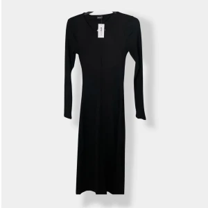 Svart ribbad långklänning Gina Tricot - Svart långklänning från Gina Tricot i ribbad stretchig kvalitet. Klänningen har lång ärm och en snygg öppen ryggdetalj som ger en cool twist. Enkel och stilren framtill, perfekt för dig som gillar minimalistisk stil med en edge.