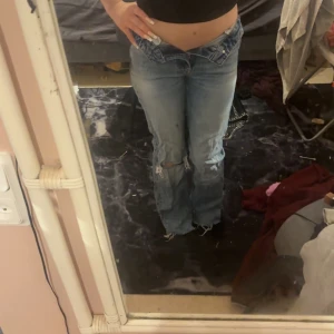 Blå slitna jeans från Gina tricot  - Ett par blå jeans från Gina tricot i klassisk tvätt med slitning och hål på ena benet. Raka ben och normal passform, tillverkade i bomull. Perfekta för en avslappnad och trendig look. Skriv för mer bilder på byxorna eller hur de sitter på! Priset kan diskuteras 💓🥰