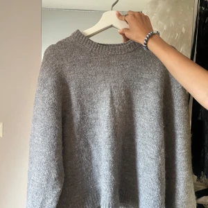 Grå stickad tröja från Gina Tricot - Mysig grå stickad tröja från Gina Tricot i storlek XS. Tröjan har en klassisk rund halsringning, lång ärm och är tillverkad i ett mjukt, fluffigt material som känns riktigt skönt mot huden. Perfekt för lager-på-lager under kyliga dagar. Det är äkta bomull, säljer för 120kr! Hör av er vid frågor🥰