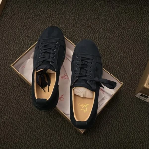 Mörkblå sneakers från Louboutin - Snygga mörkblå sneakers från Louboutin i mocka med klassisk röd sula och broderad logga baktill. Skorna har rund tå, snörning och diskreta detaljer som ger en lyxig känsla. Perfekta för dig som vill sticka ut med exklusiv streetstyle.
