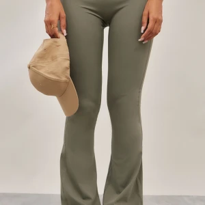 Olivgröna bootcut leggings - Snygga olivgröna leggings med bootcut och hög midja. Stretchigt och mjukt material som sitter tajt upptill och släpper ut vid bensluten. Perfekta för en trendig och bekväm look.