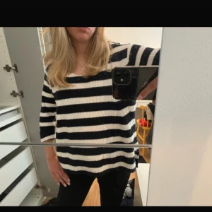 Randig stickad tröja i svart  vitt Indiska - Säljer en stickad tröja med breda svarta och vita ränder. Tröjan har trekvartsärm och en avslappnad passform. Ribbstickad struktur och rund halsringning.