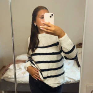 Vit och marinblå randig stickad tröja - Supermysig stickad tröja i vitt med breda marinblå ränder. Tröjan har en klassisk rund halsringning och långa ärmar. Perfekt för lager-på-lager och chill dagar. Ribbstickade muddar ger en snygg och bekväm passform.