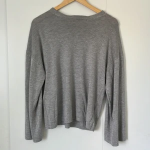 Grå långärmad tröja Gina Tricot - En enkel och stilren grå långärmad tröja från Gina Tricot. Tröjan har en avslappnad passform med rund halsringning och är tillverkad i mjukt material som passar perfekt till lager-på-lager. Perfekt för dig som gillar en clean och basic look.