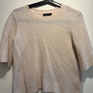 Beige stickad tröja från Stockh LM - Supermjuk och fluffig beige stickad tröja från Stockh LM. Tröjan har rund halsringning och halvlånga ärmar, perfekt för lager-på-lager. Enkel och clean design som är lätt att matcha med allt. Snygg söm längs ryggen för en extra detalj.