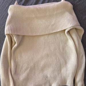 Ribbad offshoulder polotröja beige - Superfin ribbad polotröja i beige med bred krage som kan bäras offshoulder. Tröjan har lång ärm och är gjord i ett mjukt, stretchigt material som sitter snyggt på kroppen. Perfekt för dig som gillar stilrena och trendiga plagg. Storlek M men tycker den passar från xs och uppåt