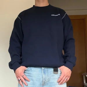 Mörkblå sweatshirt - Mörkblå sweatshirt från Tee Gold i storlek XL med tryck på bröstet 'Älvdalsbygg AB'. Den sitter som en M oversized. Tröjan har rund hals, långa ärmar och kontrastsömmar vid axlarna. Perfekt för dig som gillar en enkel och clean stil. 181 cm och 80 kg för referens. 