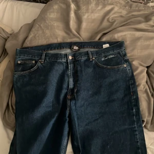 Blå jeans från Sweet Skateboarding - Säljer ett par mörkblå jeans från Sweet Skateboarding Company. Klassisk femficksmodell med raka ben och normal passform. Snygga kontrastsömmar och läderpatch bak i midjan. Perfekta för dig som gillar streetwear och skate.