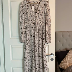 Blommig klänning Indiska  - Blommig klänning från Indiska i storlek XS, superfin men aldrig kommit till användning. Jag är 176 cm lång och den går till anklarna på mig. 