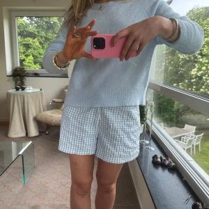 Blåvitrutiga shorts i bomull - Supersöta blåvitrutiga shorts med normal passform och låg midja. De har klassiskt rutmönster, knapp och dragkedja framtill samt är sydda i mjuk bomull. Perfekta för varma dagar och ger en fräsch sommarkänsla.