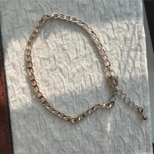 Kedjearmband i guldton - Stilrent armband med platt kedja i guldtonad metall. 