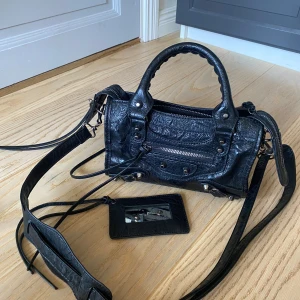 Svart handväska💓 - Svart handväska i superfint skick, det finns både handtag och lång axelrem. Väskan har fina och små detaljer, en dragkedja framtill och en tillhörande spegel. Perfekt storlek och passar till allt😍🥰 Skriv vid fler frågor och funderingar💓